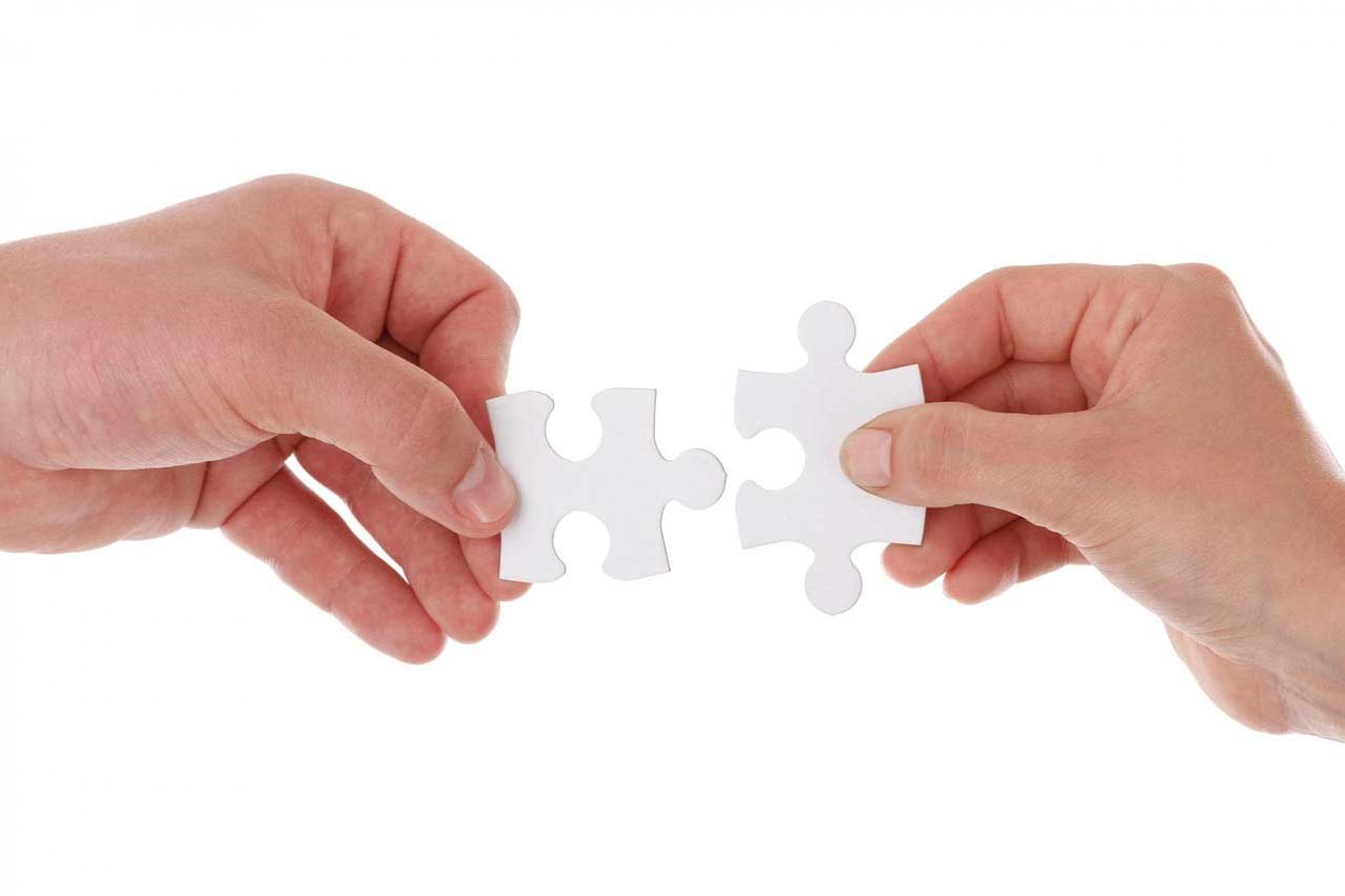 Symbolbild von zwei Händen die zwei Puzzleteile zusammenfügen wollen.
